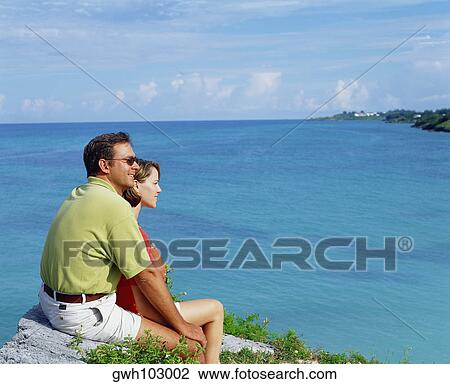 Side profile of a young couple sitting together on a rock, Bermuda View Large Photo Image Stock Image - Side profile of a young couple sitting together on a rock, Bermuda. Fotosearch