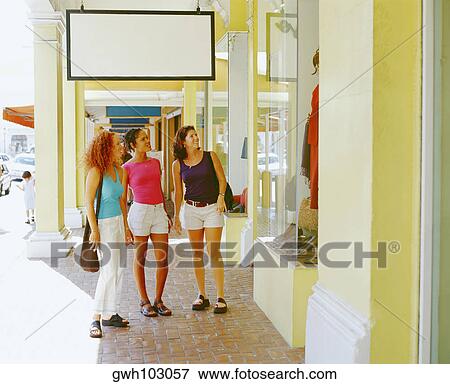 Stock Photo - Three young women looking at a window display in a market, Bermuda. Fotosearch