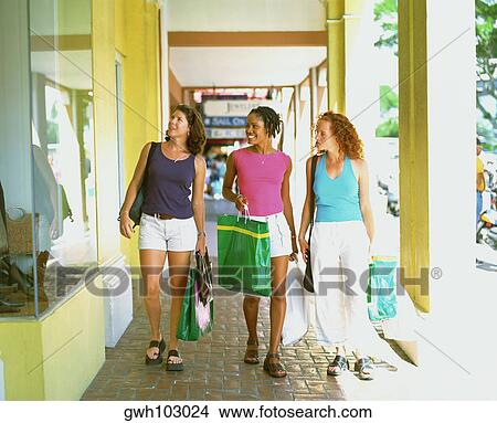 Three young women walking on a walkway and holding shopping bags, Bermuda View Large Photo Image Picture - Three young women walking on a walkway and holding shopping bags, Bermuda. Fotosearch