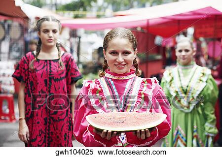 Stock Photography - Portrait of a young woman holding a slice of watermelon and smiling. Fotosearch