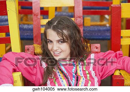 Portrait of a young woman sitting on a chair View Large Photo Image Stock Photography - Portrait of a young woman sitting on a chair. Fotosearch