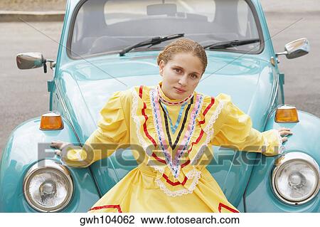 Portrait of a young woman sitting on the bumper of a car View Large Photo Image Stock Image - Portrait of a young woman sitting on the bumper of a car. Fotosearch