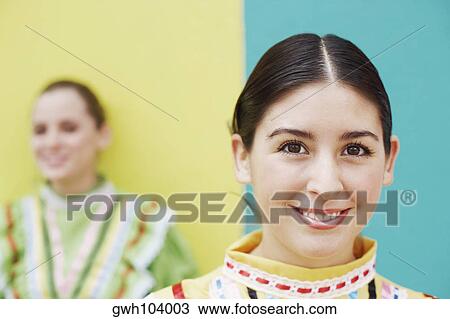Portrait of a young woman smiling with another young woman standing in the background View Large Photo Image Stock Image - Portrait of a young woman smiling with another young woman standing in the background. Fotosearch