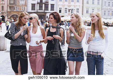 Stock Image - Group of young women walking with ice-cream cones . Fotosearch