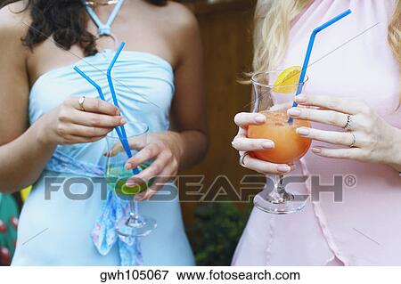 Mid section view of two women holding drinks View Large Photo Image Stock Photo - Mid section view of two women holding drinks . Fotosearch