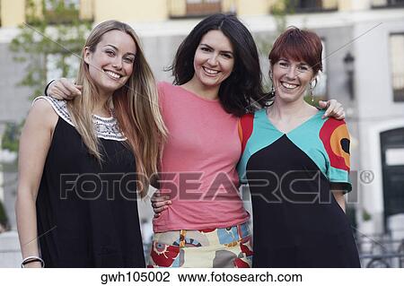 Portrait of a mid adult woman standing with her arm around two young women View Large Photo Image Stock Image - Portrait of a mid adult woman standing with her arm around two young women. Fotosearch