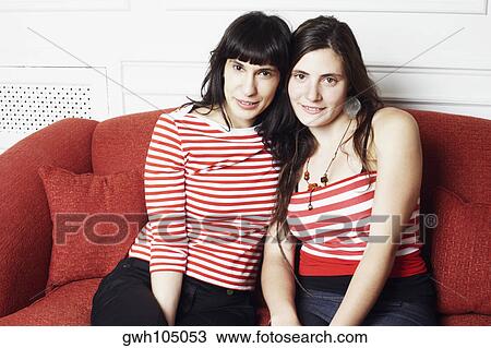 Portrait of a young woman and a mid adult woman sitting on a couch View Large Photo Image Stock Image - Portrait of a young woman and a mid adult woman sitting on a couch. Fotosearch