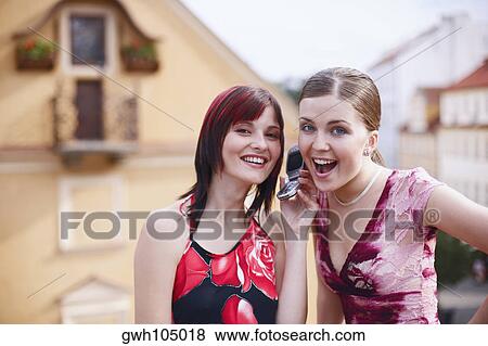Portrait of two young women listening to a mobile phone View Large Photo Image Stock Photo - Portrait of two young women listening to a mobile phone . Fotosearch
