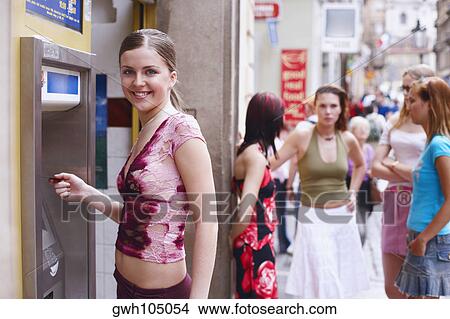 Side profile of a young woman in front of an ATM machine View Large Photo Image Picture - Side profile of a young woman in front of an ATM machine . Fotosearch