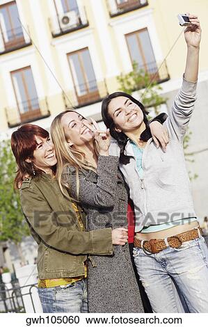 Young woman taking a photograph of herself with her two friends View Large Photo Image Stock Image - Young woman taking a photograph of herself with her two friends . Fotosearch