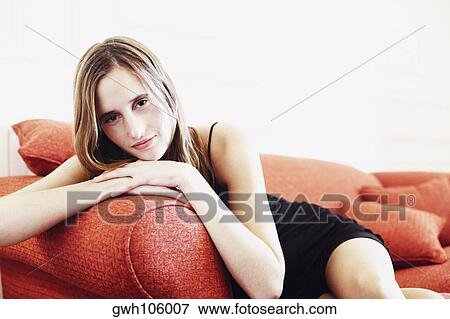Stock Photo - Portrait of a young woman lying on a couch. Fotosearch