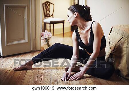 Stock Image - Young woman sitting on the floor. Fotosearch