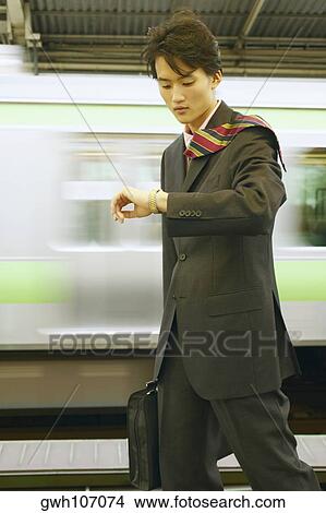 Businessman looking at his wristwatch in a subway station View Large Photo Image Picture - Businessman looking at his wristwatch in a subway station . Fotosearch