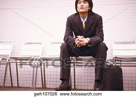 Businessman sitting on a chair with a briefcase View Large Photo Image Stock Photograph - Businessman sitting on a chair with a briefcase. Fotosearch