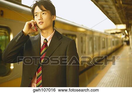 Businessman talking on a mobile phone at a subway station View Large Photo Image Stock Photograph - Businessman talking on a mobile phone at a subway station . Fotosearch
