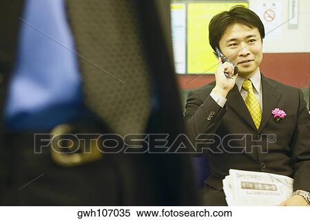 Stock Photography - Businessman talking on a mobile phone sitting. Fotosearch