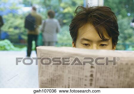 Stock Photograph - Close-up of a mid adult man reading a newspaper . Fotosearch