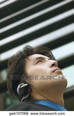 Low angle view of a businessman wearing headphones View Large Photo Image Stock Photo - Low angle view of a businessman wearing headphones. Fotosearch