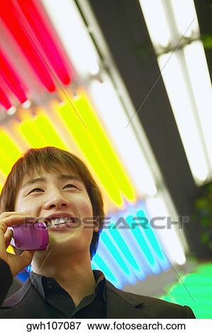 Stock Photo - Low angle view of a young man talking on a mobile phone. Fotosearch
