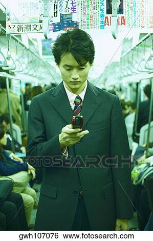 Mid adult man operating a mobile phone in a train View Large Photo Image Stock Photograph - Mid adult man operating a mobile phone in a train . Fotosearch