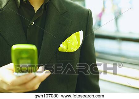 Mid section view of a young man holding a mobile phone View Large Photo Image Stock Image - Mid section view of a young man holding a mobile phone. Fotosearch