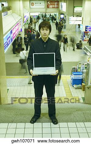 Portrait of a businessman holding a laptop View Large Photo Image Stock Image - Portrait of a businessman holding a laptop . Fotosearch