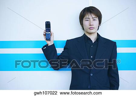 Portrait of a young man holding a mobile phone View Large Photo Image Stock Image - Portrait of a young man holding a mobile phone. Fotosearch