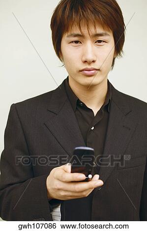 Portrait of a young man holding a mobile phone View Large Photo Image Stock Photograph - Portrait of a young man holding a mobile phone. Fotosearch