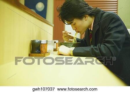 Side profile of a businessman eating noodles with chopsticks View Large Photo Image Stock Photo - Side profile of a businessman eating noodles with chopsticks . Fotosearch