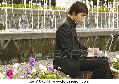 Picture - Side profile of a businessman working on a laptop . Fotosearch
