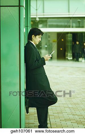 Stock Image - Side profile of a mid adult man operating a mobile phone . Fotosearch