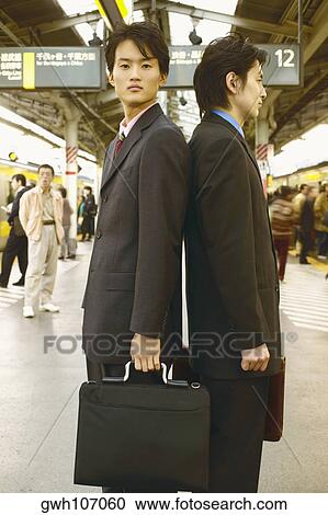 Side profile of two businessmen standing back to back in a subway station View Large Photo Image Stock Image - Side profile of two businessmen standing back to back in a subway station . Fotosearch