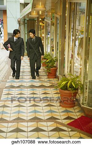 Two mid adult men walking in a corridor View Large Photo Image Stock Photo - Two mid adult men walking in a corridor . Fotosearch