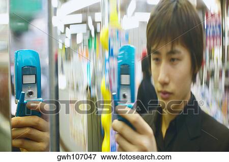 Young man holding a mobile phone View Large Photo Image Stock Photo - Young man holding a mobile phone . Fotosearch