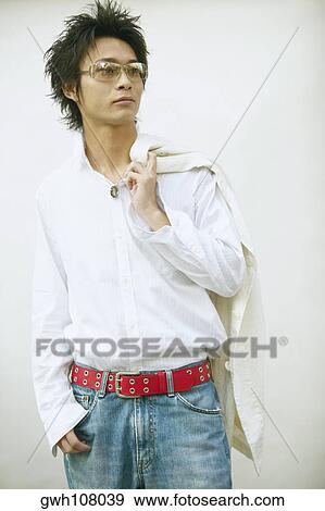 Close-up of a young man standing with his hand in his pocket and a jacket over his shoulder View Large Photo Image Stock Photo - Close-up of a young man standing with his hand in his pocket and a jacket over his shoulder. Fotosearch