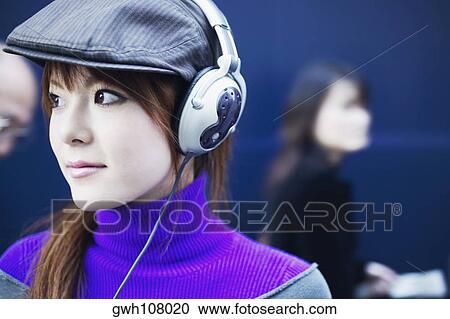 Stock Image - Close-up of a young woman wearing headphones. Fotosearch