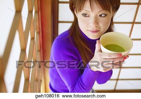 High angle view of a young woman holding a bowl of herbal tea View Large Photo Image Stock Photograph - High angle view of a young woman holding a bowl of herbal tea. Fotosearch