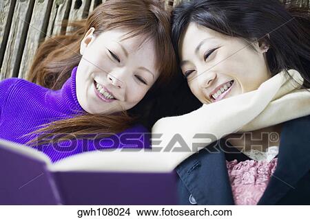 High angle view of two young women reading a book View Large Photo Image Picture - High angle view of two young women reading a book. Fotosearch