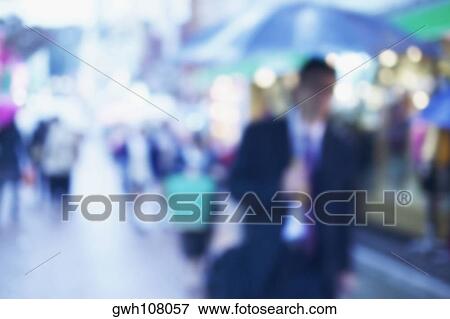Stock Photo - Man walking under an umbrella on the street, Tokyo, Japan. Fotosearch