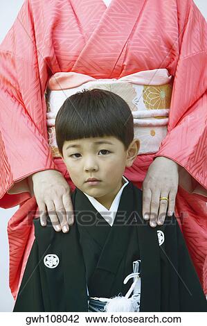 Stock Image - Portrait of a boy standing with his mother. Fotosearch
