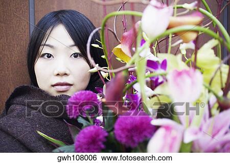 Portrait of a young woman behind flowers View Large Photo Image Stock Photograph - Portrait of a young woman behind flowers. Fotosearch