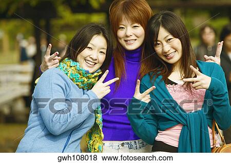 Stock Photo - Portrait of three young women showing the peace sign . Fotosearch