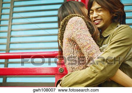 Stock Photo - Side profile of a mid adult man embracing a young woman. Fotosearch