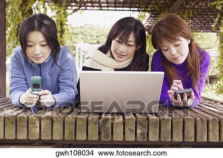 Picture - Three young women lying in front of a laptop . Fotosearch