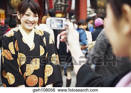 Stock Photograph - Woman taking a photograph of a young woman . Fotosearch