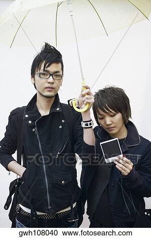 Young man and a young woman standing under an umbrella View Large Photo Image Stock Image - Young man and a young woman standing under an umbrella. Fotosearch