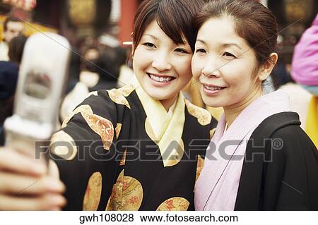Stock Photo - Young woman and her mother taking a photograph of themselves . Fotosearch