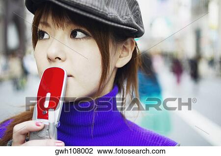 Stock Image - Young woman holding a mobile phone . Fotosearch