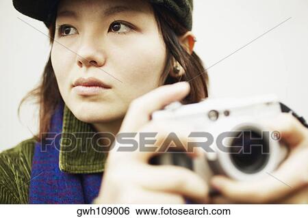 Close-up of a young woman holding a camera View Large Photo Image Stock Photograph - Close-up of a young woman holding a camera. Fotosearch