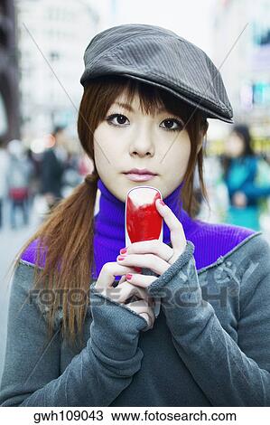Portrait of a young woman holding a mobile phone View Large Photo Image Stock Image - Portrait of a young woman holding a mobile phone . Fotosearch